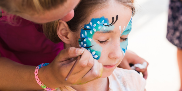 woman painting a butterfly on a girls face at a carnival