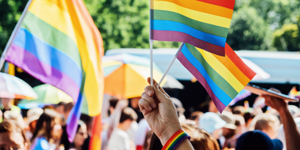 Pride Month Events - crowd of people at a Pride Event holding rainbow flags